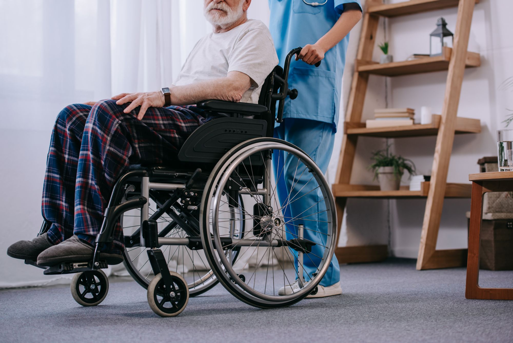 Eine Krankenschwester hilft einem älteren Mann im Rollstuhl.